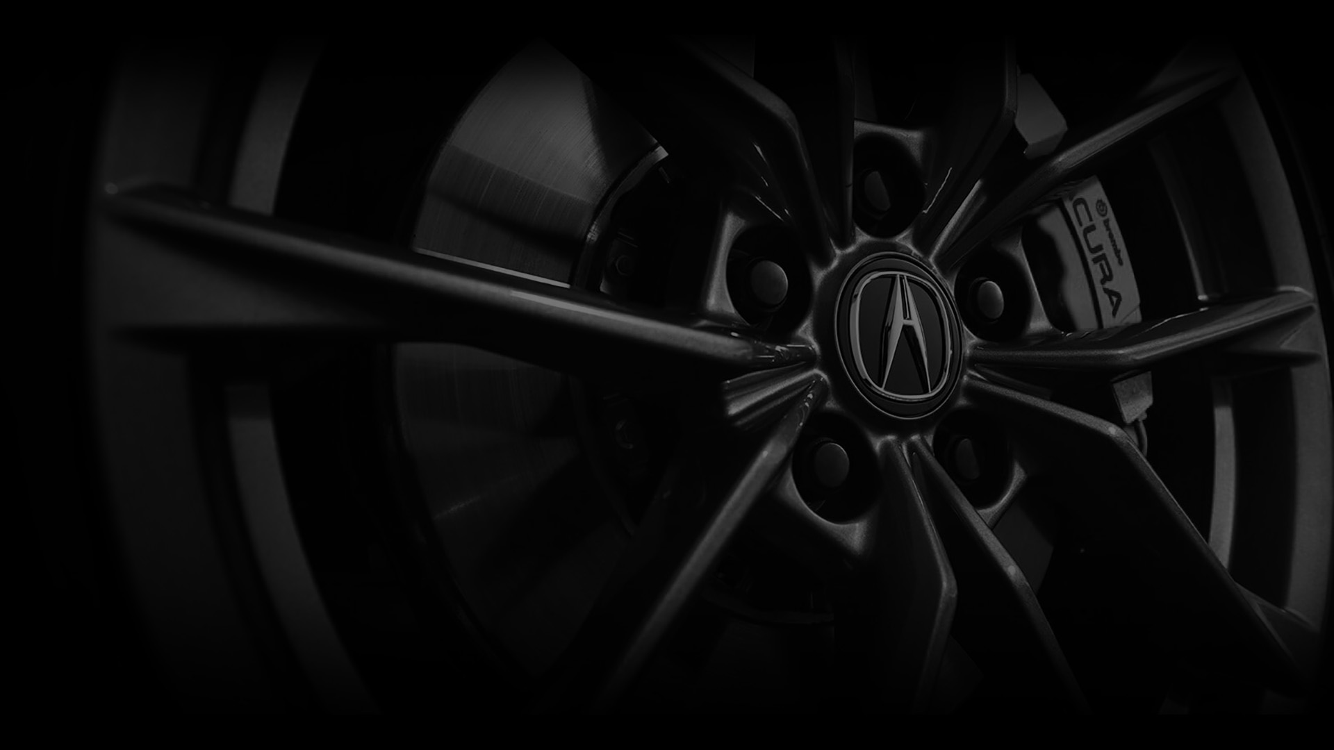 Close-up of a dark wheel rim with an Acura logo and sleek spokes.